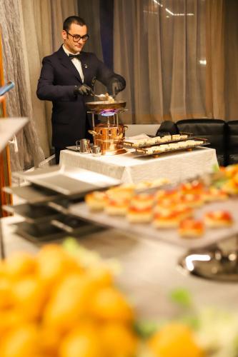 a man in a suit standing behind a table with food at Style Hotel Grifone in Madonna di Campiglio