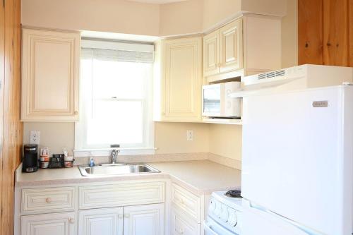 uma cozinha com armários brancos, um lavatório e um frigorífico em Surf Villa Apartments em Ocean City