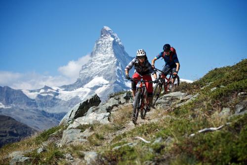 two people riding bikes on a mountain trail at BaseCamp Hotel in Zermatt