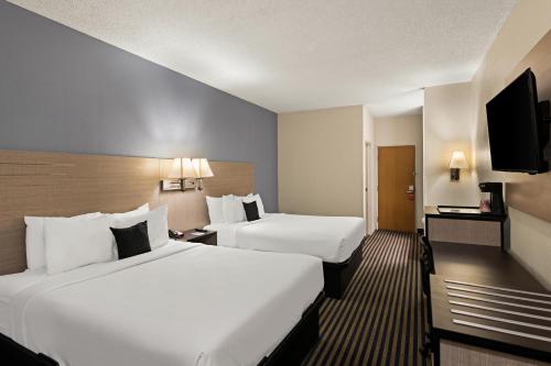a hotel room with two beds and a flat screen tv at Red Lion Inn & Suites Gretna - Omaha SW in Gretna