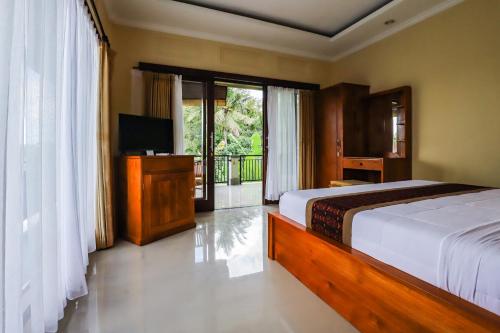 a bedroom with a bed and a television and a balcony at Big Stone House 7 - 6 min Center and 500m Parq Ubud in Ubud