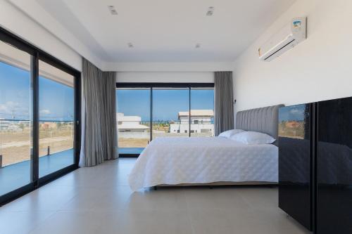 um quarto com uma cama e grandes janelas de vidro em Bosque da Praia #105 - Casa em Jacumã by Carpediem em Jacumã