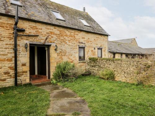 an old brick building with a door and a wall at Stable Cottage in Moreton in Marsh
