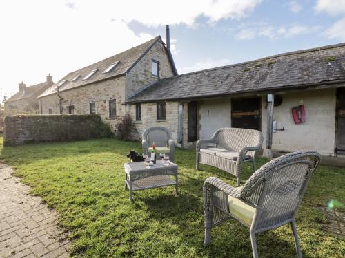 a yard with chairs and a table with a cat on it at Stable Cottage in Moreton in Marsh
