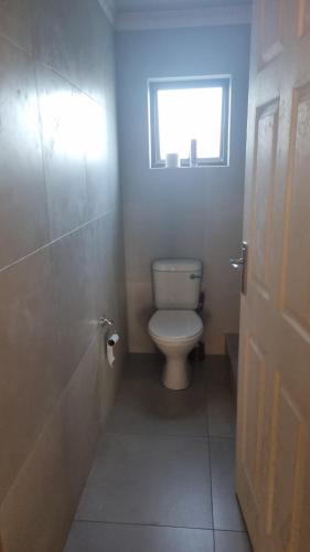 a bathroom with a toilet and a window at Airport Airbnb family units in Richards Bay