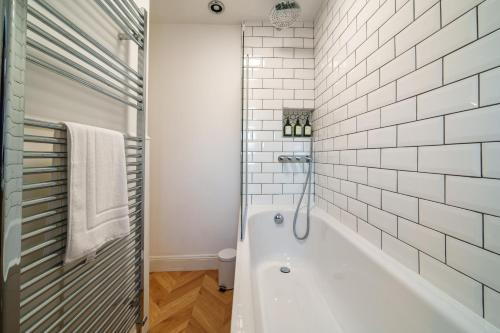 a white bathroom with a tub and a shower at Meadow View - Cosy townhouse with patio garden & parking in Kendal