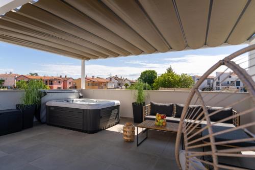 a patio with a hot tub on a balcony at Costa Deluxe in Funtana