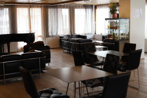 una sala d'attesa con tavoli, sedie e pianoforte di Style Hotel Grifone a Madonna di Campiglio