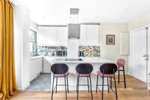 a kitchen with a white island with four stools at Boulogne Billancourt - Schuman 1bdr in Boulogne-Billancourt