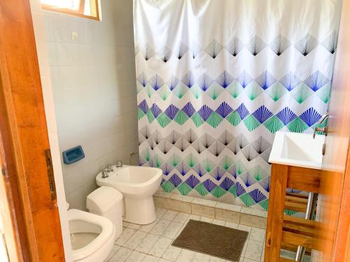 a bathroom with a toilet and a shower curtain at Cabañas Los 5 Sauces in Santa Clara del Mar