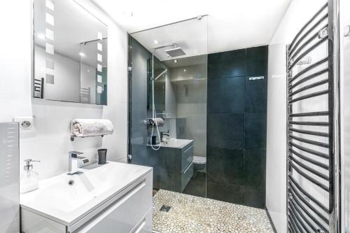 een witte badkamer met een wastafel en een douche bij Notre Dame des Champs - Vavin 1bdr in Parijs