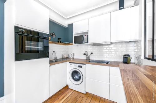une cuisine avec des armoires blanches et une laveuse et une sécheuse dans l'établissement Gros Caillou - Bourdonnais 1bdr, à Paris