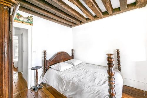 - une chambre avec un lit doté d'un cadre en bois dans l'établissement Ile Saint Louis - Quai d'Orleans 2bdr by B'Your Home, à Paris