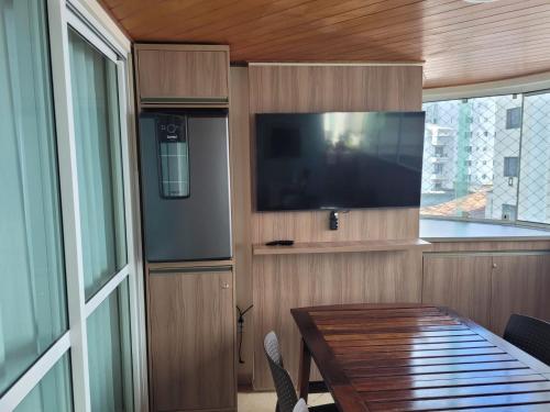 sala de estar con TV y mesa con mesa. en Diferenciado - 210m Privativos, Terraço - Cervejeira - 3 Quartos - 2 banheiros, en Balneário Camboriú