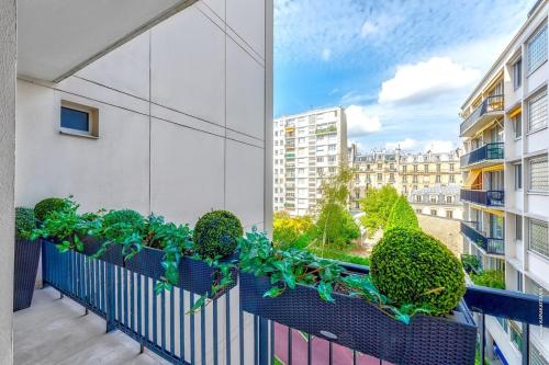 - un balcon avec des plantes dans un bâtiment dans l'établissement Maillot Ternes - Saint Ferdinand 3bdr, à Paris