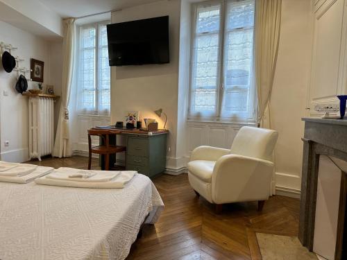 Cette chambre comprend un lit, une chaise et une télévision. dans l'établissement Chambre de charme au coeur du vieux Valence - Confort & Calme, à Valence