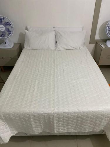 uma cama branca com lençóis e almofadas brancos em Quarto e Sala Beira Mar Maceió em Maceió