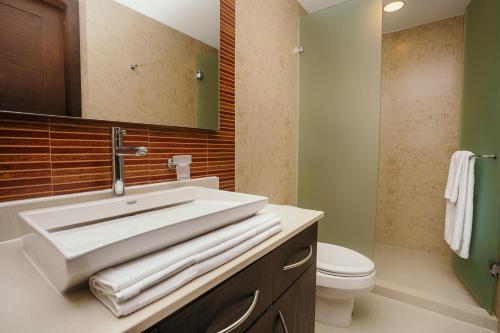 a bathroom with a sink and a toilet and a mirror at Mareazul Beach Front Condos At playa del Carmen in Playa del Carmen