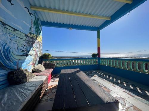 einen Balkon mit einer Bank und einem Gemälde an der Wand in der Unterkunft Boilers Surf House in Tamri