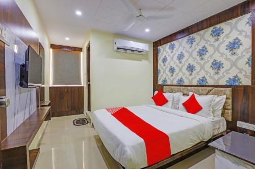 1 dormitorio con 1 cama grande con almohadas rojas en OYO Hotel Golden, en Vadodara