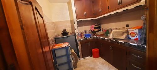 eine Küche mit Holzschränken und einem schwarzen Kühlschrank in der Unterkunft Dar Salam in Ad-Dakhla