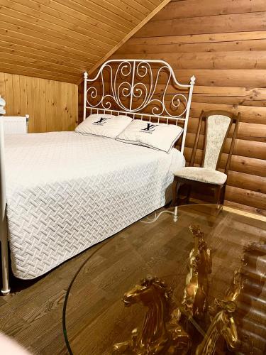 a bedroom with a white bed and a chair at Садиба Карпат in Verkhovyna