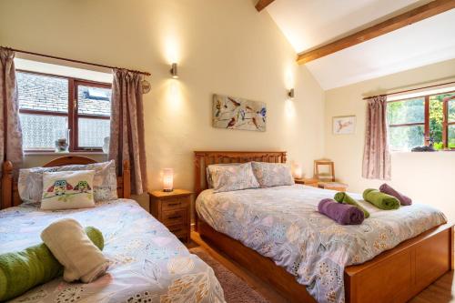 a bedroom with two beds and two windows at Todd Cottage - Ideal for exploring Wasdale & Wastwater in Santon Bridge