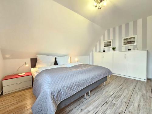 a white bedroom with a bed and a red table at Mienhus Apartments Ferienwohnung Famke in Norden