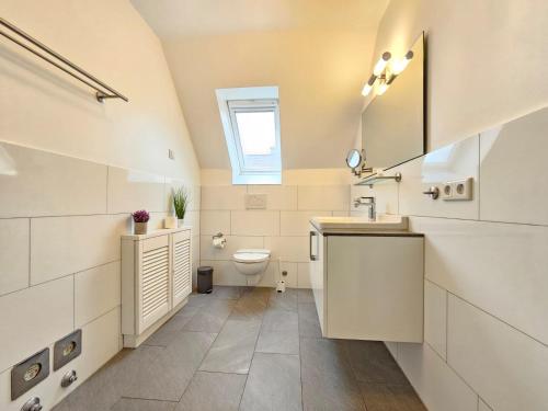 Baño blanco con lavabo y aseo en Mienhus Apartments Ferienwohnung Famke, en Norden