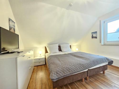 a bedroom with a bed and a flat screen tv at Mienhus Apartments Ferienwohnung Jantje in Norden