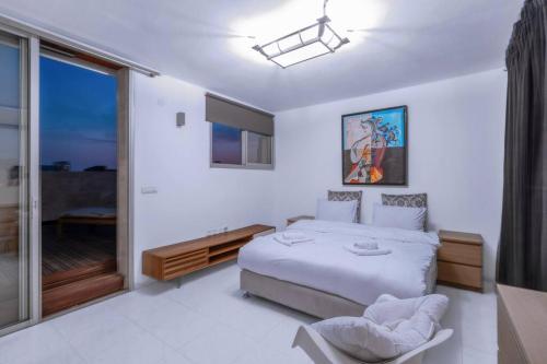 um quarto branco com uma cama e uma porta de vidro deslizante em Penthouse Mapu - Mamad em Tel Aviv