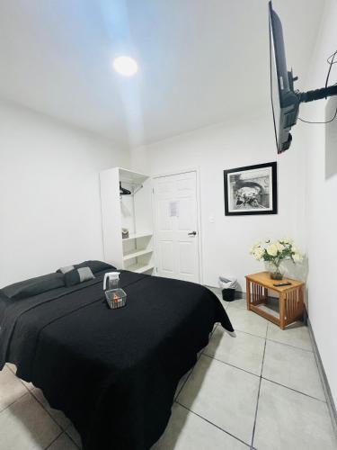 a bedroom with a black bed and a tv at Casa Ambar in Tijuana