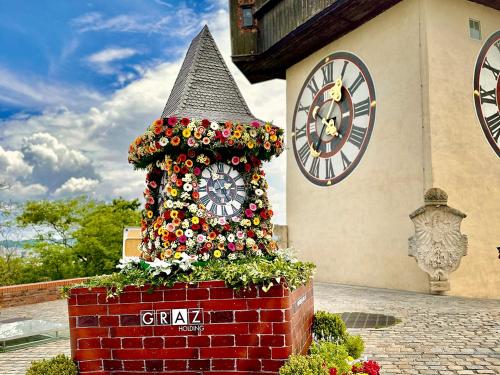 a clock with flowers on it in front of a building at Das Rizzi in Grössing