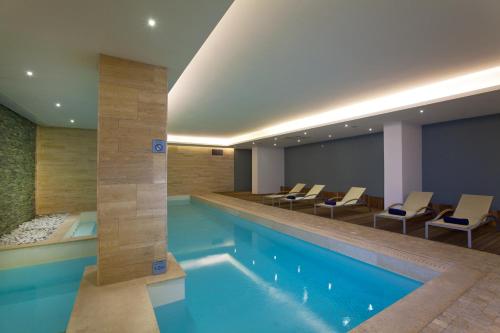 a swimming pool in a hotel room with chairs around it at The George, Urban Boutique Hotel in St Julian's