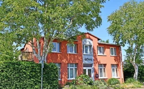 a red building with trees in front of it at Appartementhaus auf Moenchgut in Thiessow