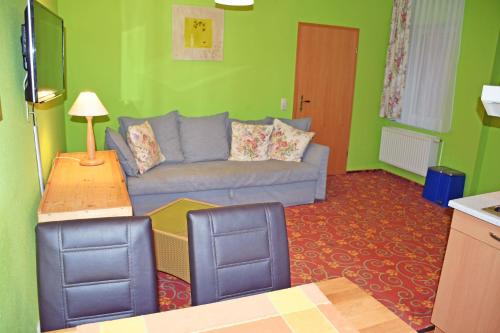 a living room with a blue couch and green walls at Appartementhaus auf Moenchgut in Thiessow