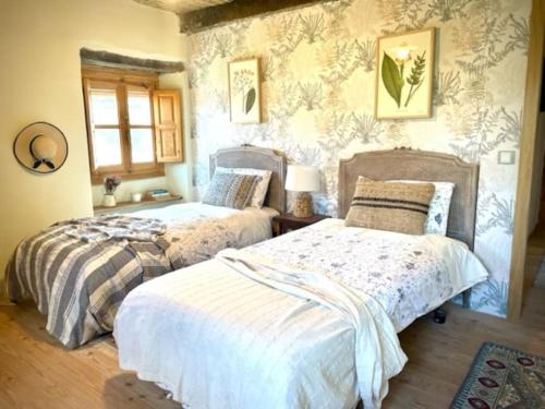 a bedroom with two beds in a room with wallpaper at Encantadora casa de pueblo 