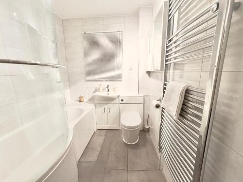 a white bathroom with a toilet and a sink at Peacock Court in London