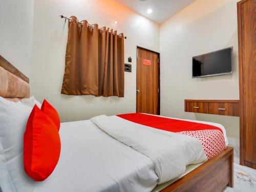 a bedroom with a bed with red pillows and a television at Hotel RS in Nagpur