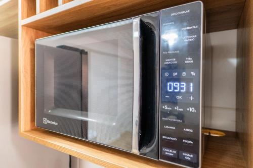 a microwave oven sitting on a wooden shelf at Até 5Hóspedes,Garagem, Elevador, Piscina, JrCatito in Brasilia