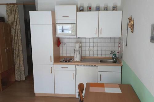 ObergünzburgにあるGemütliche Wohnung nahe Kempten (Obergünzburg)の小さなキッチン(白いキャビネット、テーブル付)