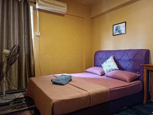 a bed in a room with a purple head board at M.FR Homestay Pangsapuri Putra Damai in Putrajaya