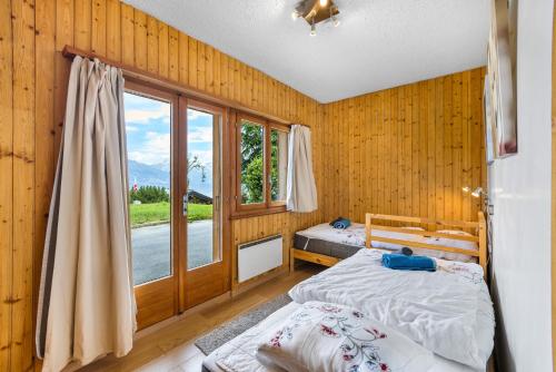a bedroom with two beds and a large window at Les 4 Abeilles - 6 pers - bien amenage in Nendaz