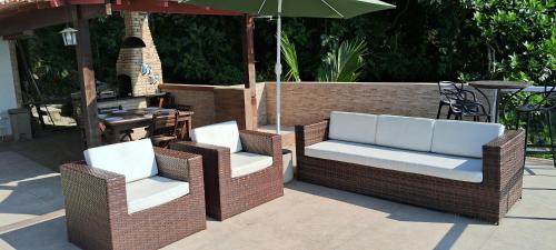 two wicker chairs and an umbrella on a patio at Casa Martureza in Angra dos Reis