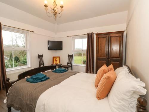 a bedroom with a large white bed with a chandelier at Argoed in Holywell
