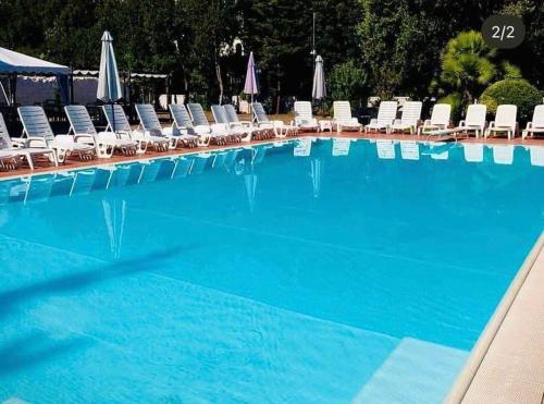 a large blue swimming pool with chairs and umbrellas at IN BLOOM ROOM b&b in Castel San Giorgio
