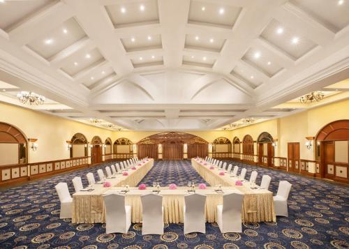 a long banquet hall with white tables and chairs at Taj Exotica Resort & Spa, Goa in Benaulim
