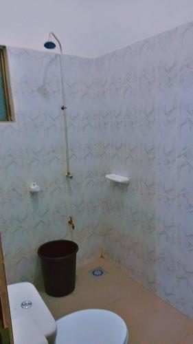 een witte badkamer met een toilet en een emmer bij Guest house AKPAKPA in Cotonou