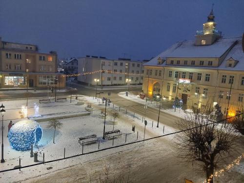 a city square with a fountain in the snow at night at Apartament przy Rynku in Olsztynek