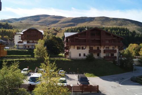 a large building with cars parked in a parking lot at Résidence Chalet d'Or by Leavetown Vacations in Les Deux Alpes